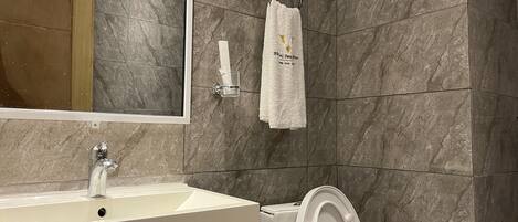 Un baño con lavamanos, espejo, toallero y retrete.