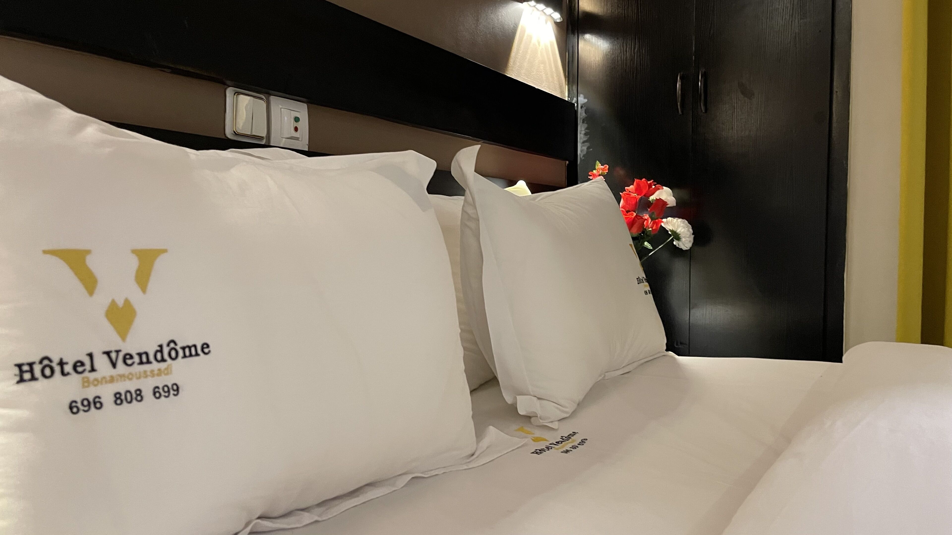 A hotel bed with white bedding and a logo on the pillow.
