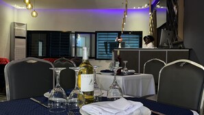 A dining area with a table set for two, featuring wine glasses, a bottle of wine, and a menu.