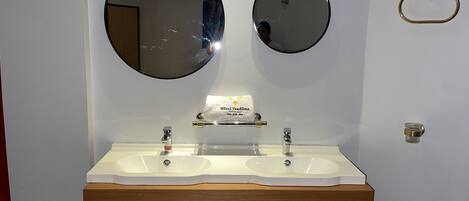 A bathroom with two sinks, a mirror, and a towel dispenser.