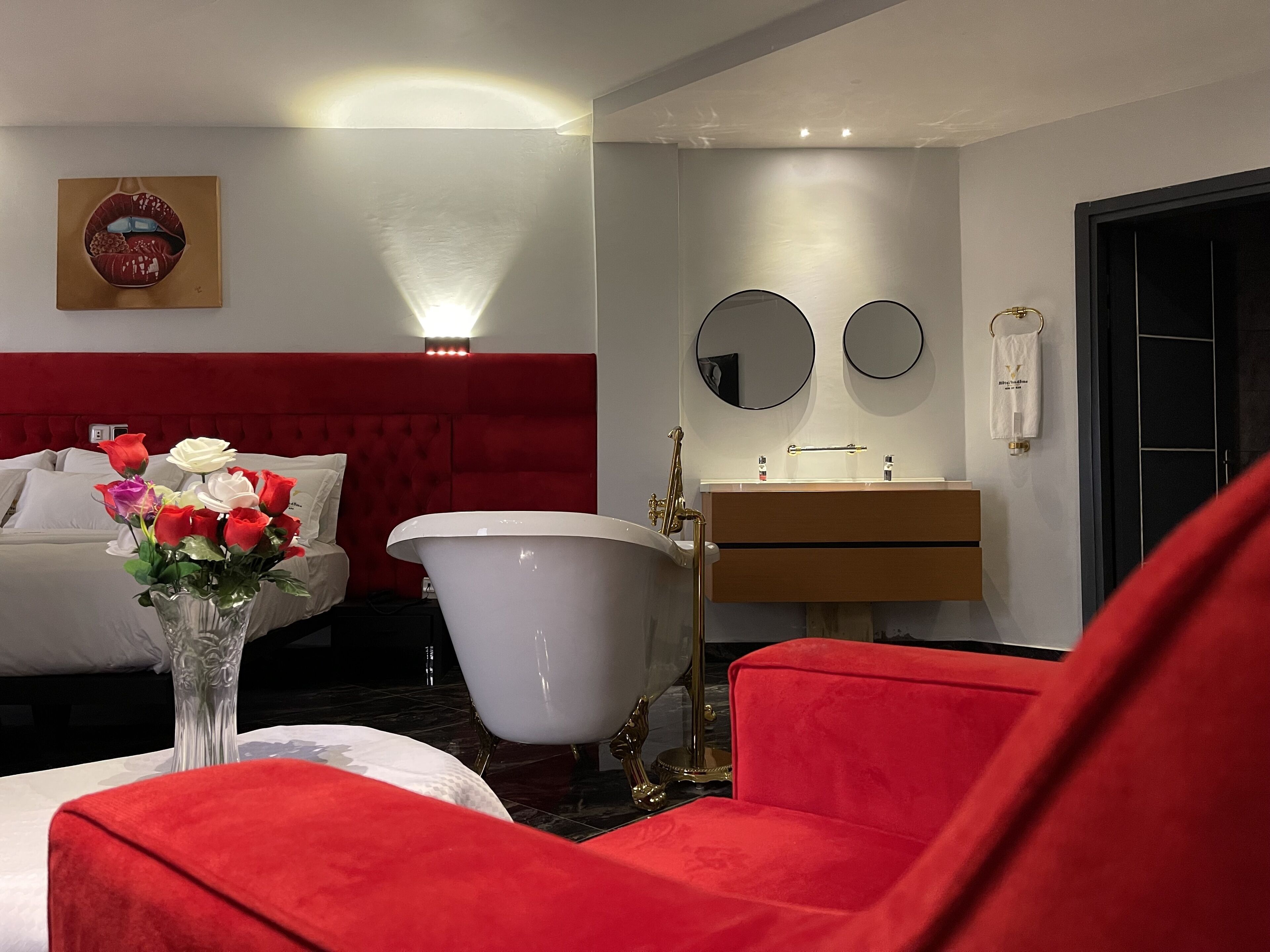 Un baño moderno con bañera, tocador con espejo y sillón tapizado en rojo.