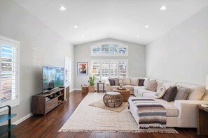 A spacious living room with a large television, a sofa, a coffee table, and a decorative rug.