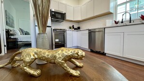 Cocina moderna con armarios blancos, electrodomésticos de acero inoxidable y una escultura decorativa de un animal dorado en el suelo.