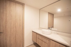 A modern bathroom with a wooden vanity, a large mirror, and a white sink. - Modern and Spacious Apartment Best Location in Bocagrande (Cartagena)