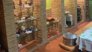 Une pièce aux murs de briques, avec des étagères remplies de verrerie et une table sur laquelle se trouve un pot.
