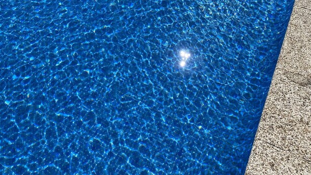 Une piscine rectangulaire à l’eau d’un bleu limpide, avec un motif circulaire au centre.