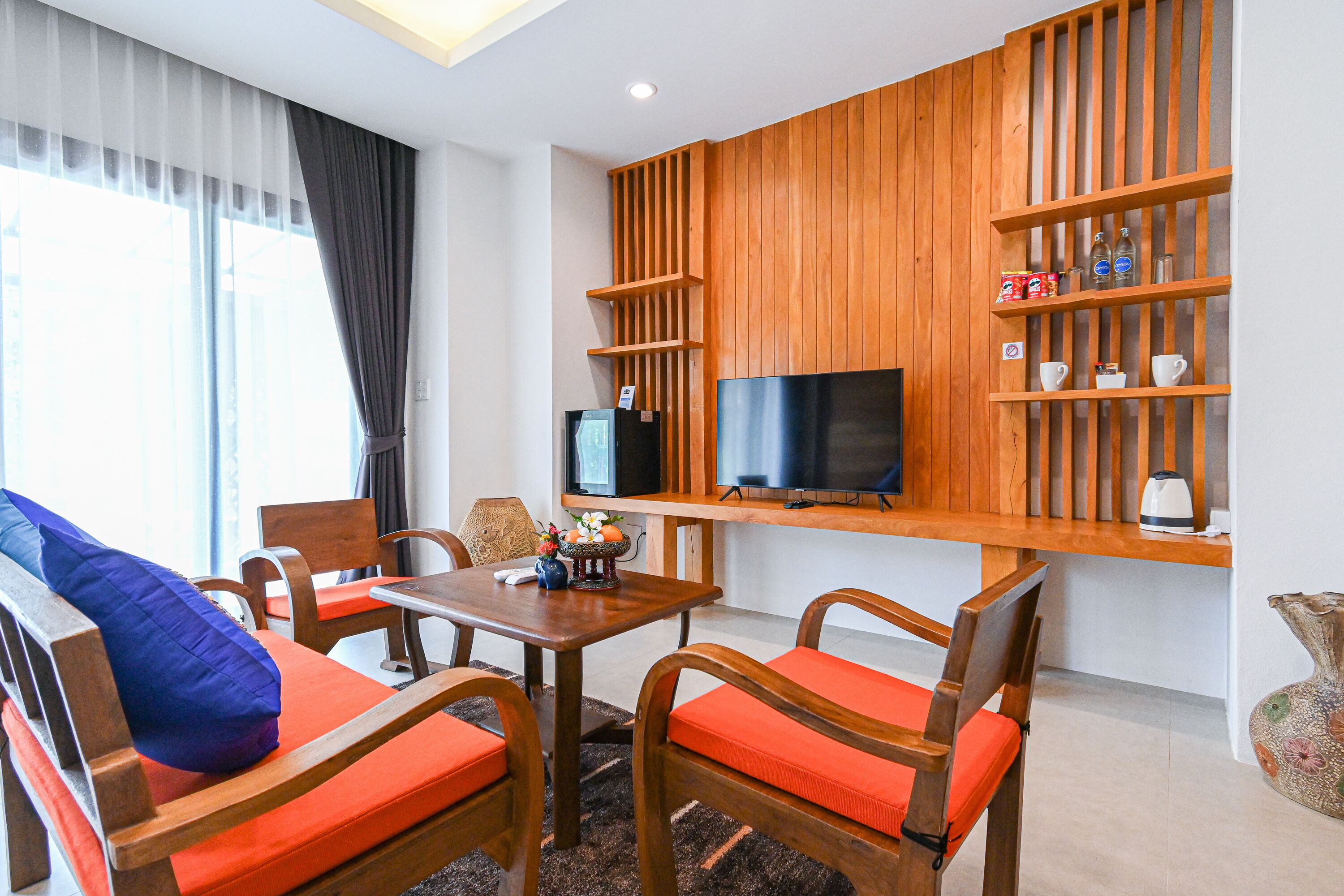 A modern living room with wooden furniture, a flat-screen TV, and a shelf with decorative items.