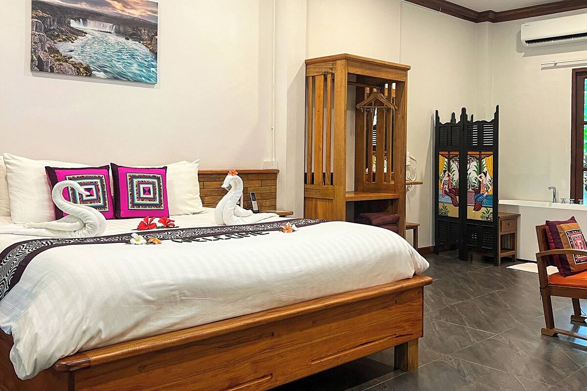 A bedroom with a wooden bed, a large window, and a painting of a waterfall.
