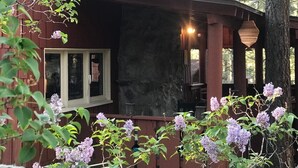 A rustic cabin with a stone fireplace, wooden porch, and a view of the surrounding forest. - Rustic Retreat|Pets OK, Near Village, Fireplace (Wrightwood)