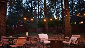 An outdoor patio with wicker chairs, a wooden table, and a fire pit. - Peaceful Pines Stuga Near Ski Resort & Village (Wrightwood)