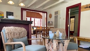 A cozy room with two upholstered chairs, a glass table, and a rustic wooden centerpiece. - Peaceful Pines Stuga Near Ski Resort & Village (Wrightwood)