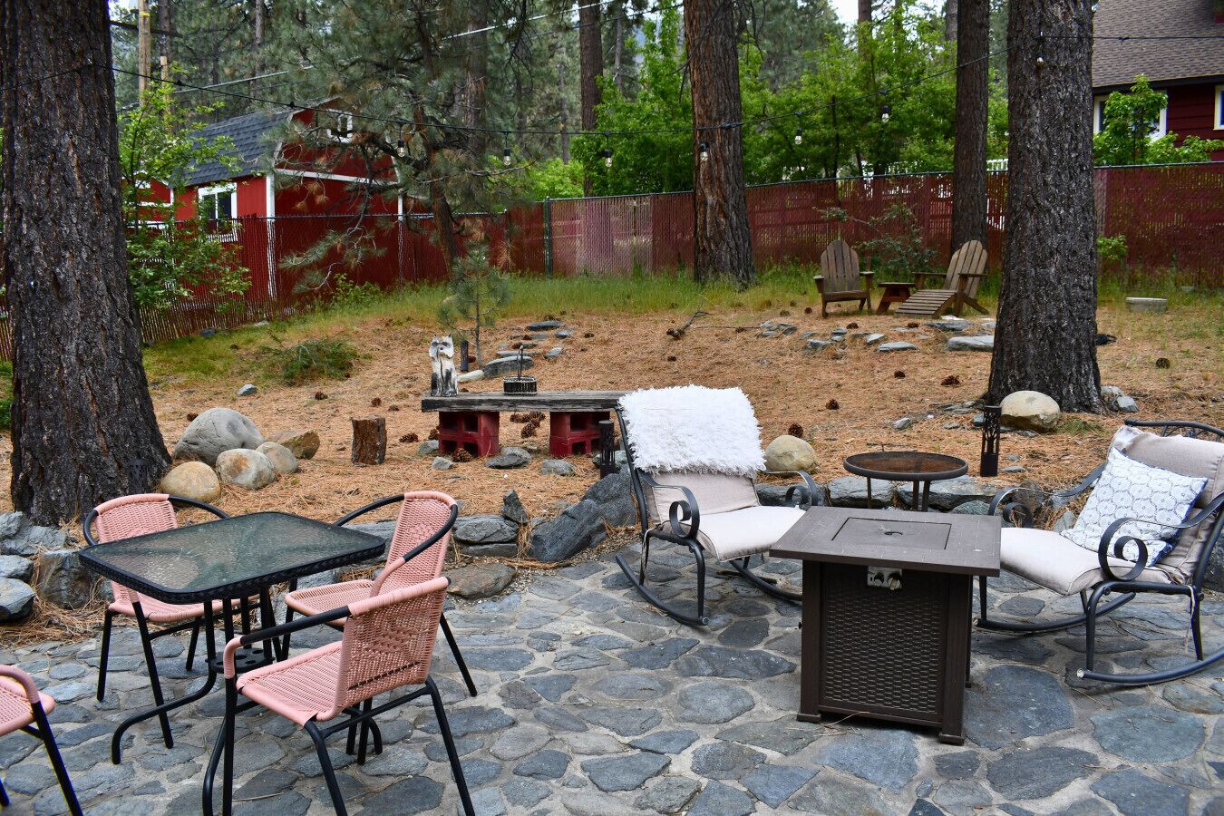 Eine Außenpatio mit Steinböden, Korbstühlen, einem Tisch und einer Feuerstelle.