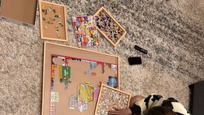 A person sitting on a carpeted floor surrounded by various puzzles and puzzle boxes. - Wheelchair Access, Near Ski & Snow Play, Pets OK! (Wrightwood)