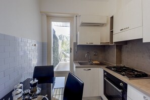A compact kitchen with a gas stove, sink, and a small dining area with a table and chairs.