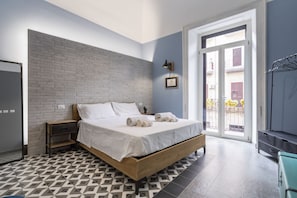 A bedroom with a bed, a nightstand, a wardrobe, and a view of the outside. - GuestHost - Cozy apartment equipped with all comforts and able to accommodate up to 4 people. The flat is located in a very central position: we are in fact a 10-minute walk from Piazza Maria Immacolata, just over 15 minutes from the Archaeological Museu (Taranto)