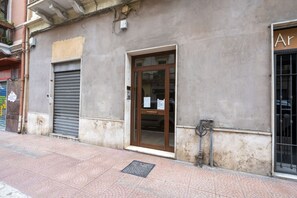 Un edificio con una puerta metálica cerrada, entrada por puerta de cristal y un letrero visible en la pared.