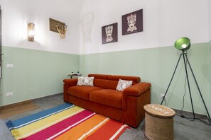 Una habitación con un sofá, un tapete a rayas de colores, una lámpara y decoración en la pared.
