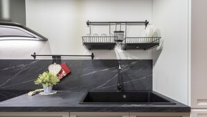 A kitchen with a black marble countertop, a sink, and two wire baskets mounted on the wall. - GuestHost - Cozy apartment equipped with all comforts and able to accommodate up to 4 people. The flat is located in a very central position: we are in fact a 10-minute walk from Piazza Maria Immacolata, just over 15 minutes from the Archaeological Museu (Taranto)