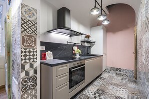 Una cocina moderna con estufa negra, horno empotrado, extractor de humos negro y encimera con lavabo.
