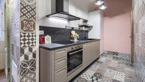 A modern kitchen with a black stove, a built-in oven, a black range hood, and a countertop with a sink. - GuestHost - Cozy apartment equipped with all comforts and able to accommodate up to 4 people. The flat is located in a very central position: we are in fact a 10-minute walk from Piazza Maria Immacolata, just over 15 minutes from the Archaeological Museu (Taranto)