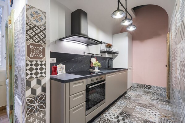 A modern kitchen with a black stove, a built-in oven, a black range hood, and a countertop with a sink.