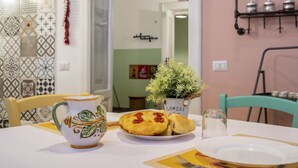 A dining table with a pitcher, a plate with food, and a potted plant. - GuestHost - Cozy apartment equipped with all comforts and able to accommodate up to 4 people. The flat is located in a very central position: we are in fact a 10-minute walk from Piazza Maria Immacolata, just over 15 minutes from the Archaeological Museu (Taranto)