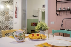 A dining table with a pitcher, a plate with food, and a potted plant. - GuestHost - Cozy apartment equipped with all comforts and able to accommodate up to 4 people. The flat is located in a very central position: we are in fact a 10-minute walk from Piazza Maria Immacolata, just over 15 minutes from the Archaeological Museu (Taranto)