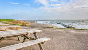 Ein Picknicktisch an einem befestigten Wegesrand direkt am Meer, mit Blick auf den Ozean und eine Wiese.