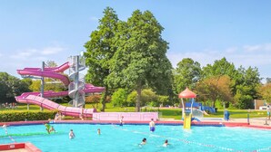 Ein Schwimmbecken mit mehreren Wasserrutschen und einem Spielbereich.