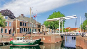 Ein Kanal mit einem angedockten grünen Boot, einer Brücke und Gebäuden mit Flaggen.