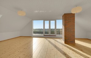Enjoy a room with a high ceiling, large windows, and a brick column, offering a view of the outdoors.