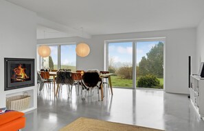 Relax in this serene space with a large dining table and a view of the surrounding green landscape.