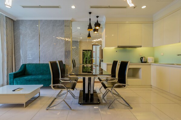 A modern living room with a teal sofa, a glass-top dining table, and black chairs.