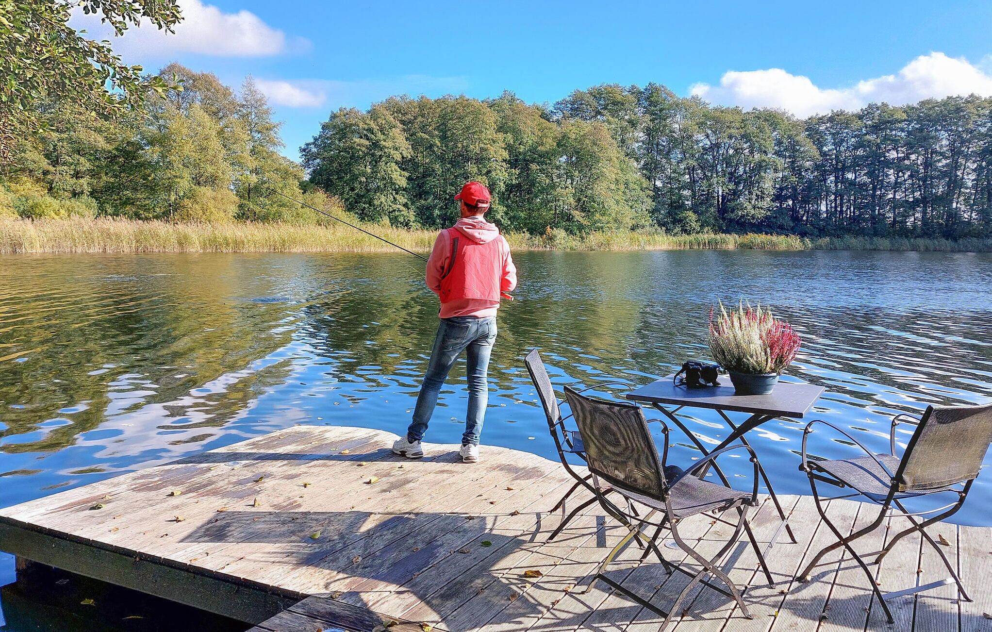 Een houten steiger die zich uitstrekt over een rustig meer, met een persoon aan het einde.