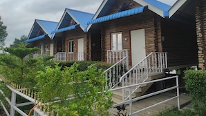 A row of log cabin-style cabins with blue roofs and white railings. - Chang's Resort (Guwahati)