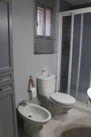 A bathroom with a toilet, bidet, and a window with blinds. - Casa Rural, Piscina, Chimenea, Barbacoa (Córdoba)