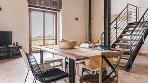 A spacious dining area with a wooden table and chairs, a large window with a view, and a staircase with a metal railing.