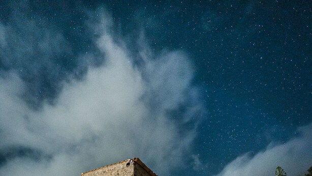 A stone building with a staircase leading up to it, under a starry night sky.