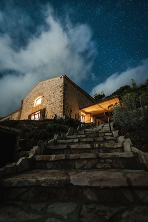 A stone building with a staircase leading up to it, under a starry night sky.