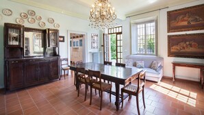 A dining area with a large wooden table, chairs, and a chandelier. There is a sofa and a painting on the wall. - Villa L'Oleandra with Pool up to 12 People (Volta Mantovana)