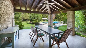 An outdoor patio with a table and chairs, a ceiling fan, and a view of a swimming pool and garden. - Villa L'Oleandra with Pool up to 12 People (Volta Mantovana)