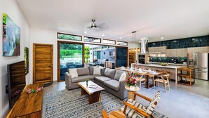 A modern living room with a sectional sofa, dining area, and kitchen. - Casa Dos Playas, private pool with direct access to 2 beaches! (Tamarindo)