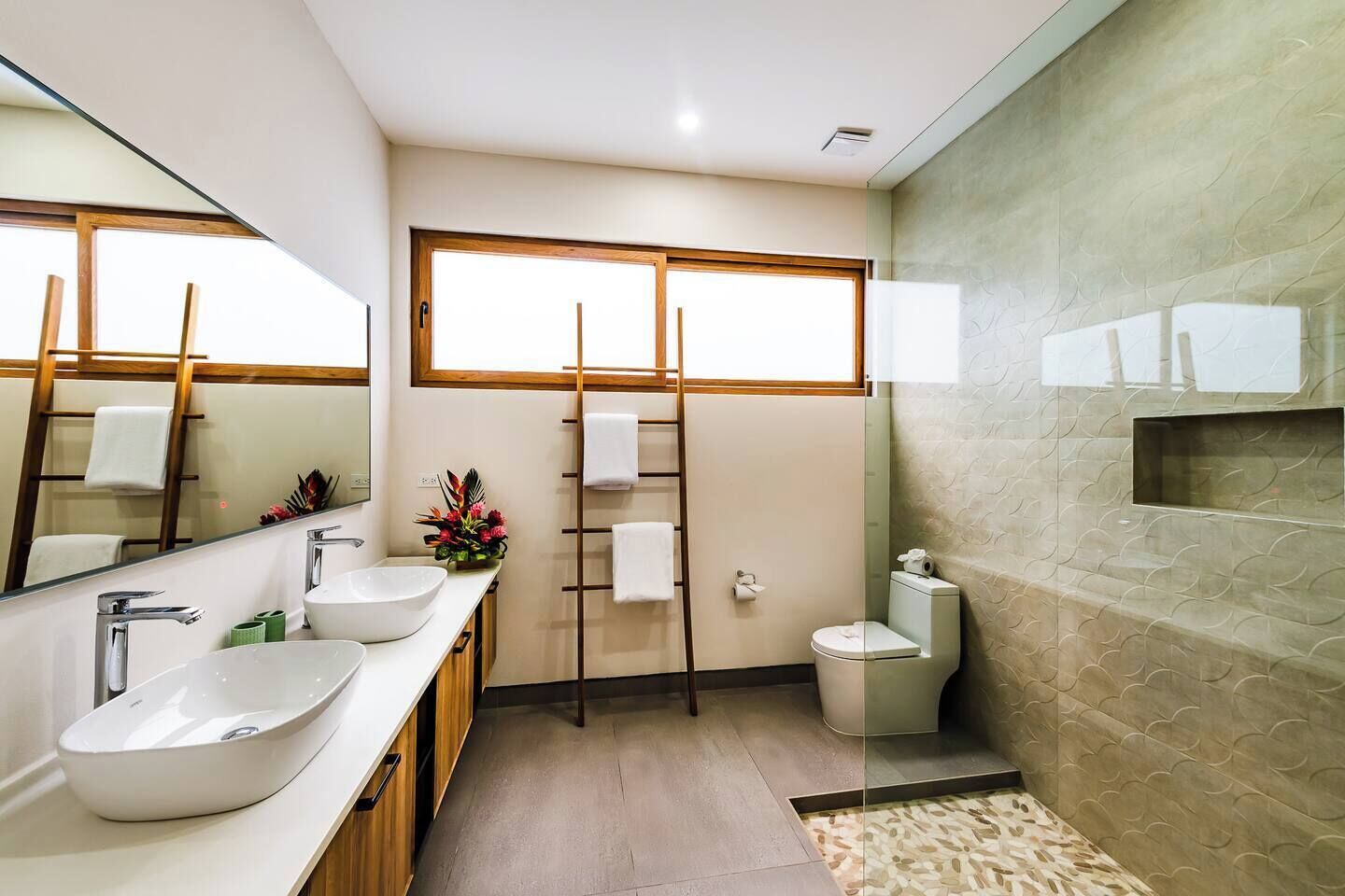Un bagno moderno con uno specchio grande, un lavandino, un WC e una finestra.