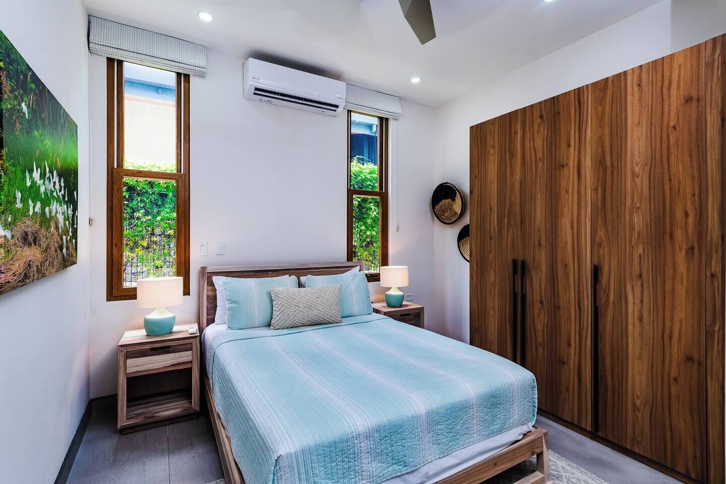 Een slaapkamer met een bed, nachtkastjes, een airconditioner en een kledingkast.