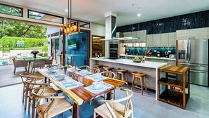 A modern kitchen with a large island, stainless steel appliances, and a view of a pool and garden. - Casa Dos Playas, private pool with direct access to 2 beaches! (Tamarindo)