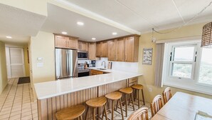 Une cuisine moderne avec un îlot central, des tabourets en bois et une table à manger.