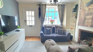 A living room with a sofa, a television, a fireplace, and a window with curtains. - Inviting 2-bed Cottage in Windsor (Windsor)