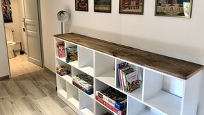 Un corridoio con un mobiletto in legno che espone libri e poster di viaggi raffiguranti città come L'Avana, Rio de Janeiro, Tokyo e Los Angeles.