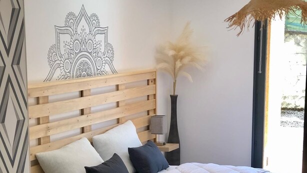 Una camera da letto con una testiera in legno, una coperta trapuntata bianca e due cuscini.