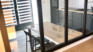 Una cucina moderna con microonde, forno e ventilatore. Si intravede un'area pranzo con tavolo e sedie attraverso una finestra.